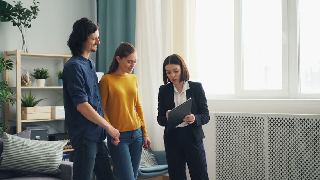 Maklerin bespricht Unterlagen mit einem Paar bei der Wohnungsbesichtigung